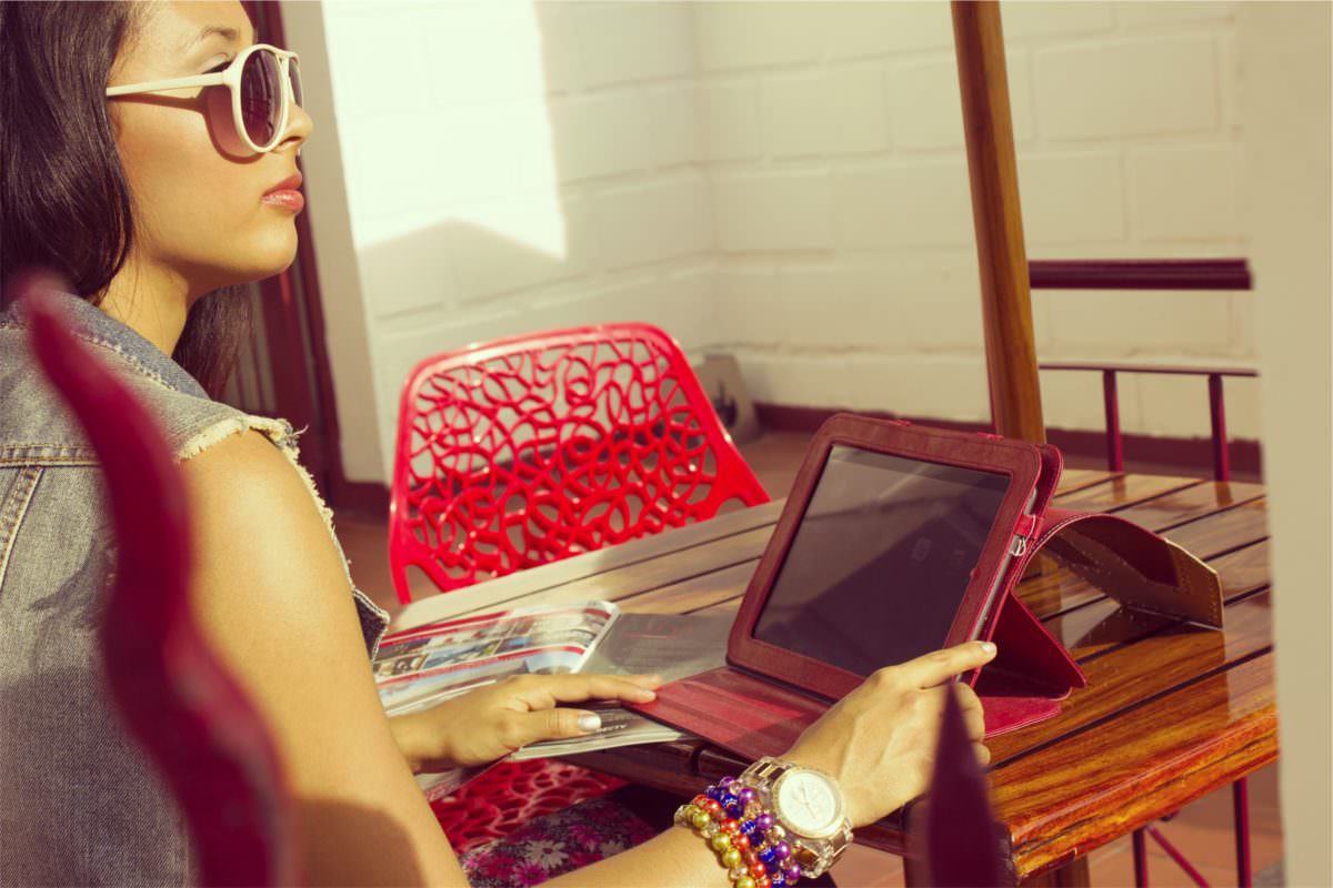 woman working from her tablet sitting outside at a wooden table