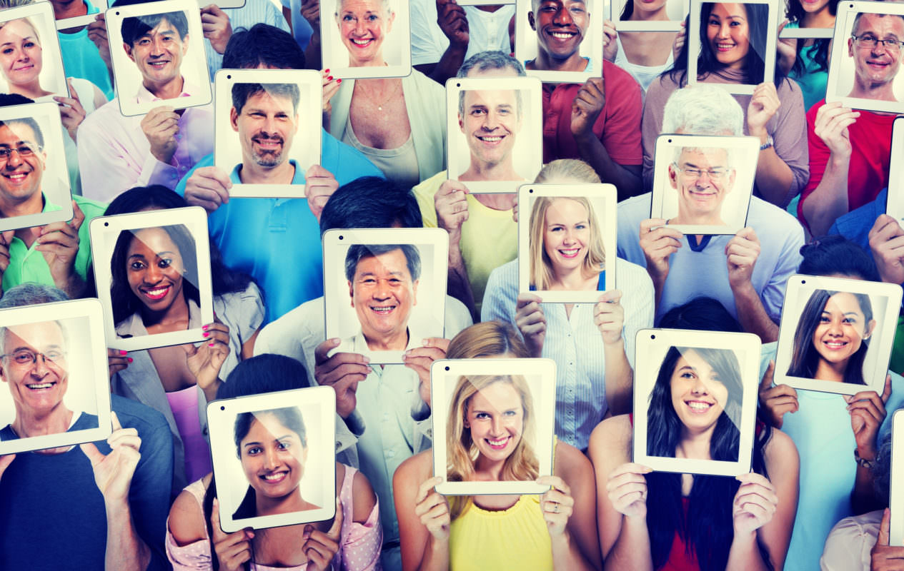 Many people holding up tablets in front of their faces with their pictures on the back