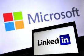 A computer screen displaying the LinkedIn logo in front of a wall with Microsoft displayed on it