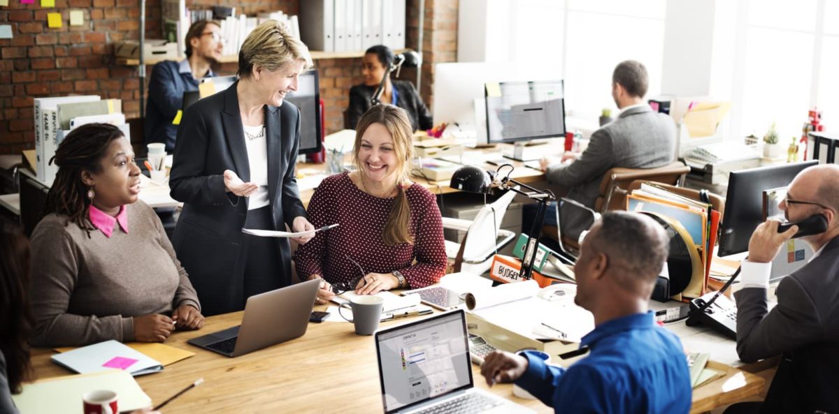 A group of co-workers smiling and working together around a table